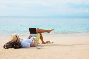 Man,working,on,laptop,computer,while,relaxing,on,the,beach